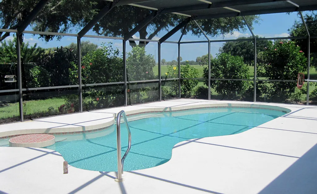 Inside a screened pool enclosure in Sarasota, Florida, with a clean pool deck