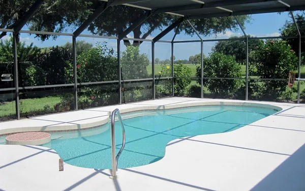 Inside a screened pool enclosure in Sarasota, Florida, with a clean pool deck
